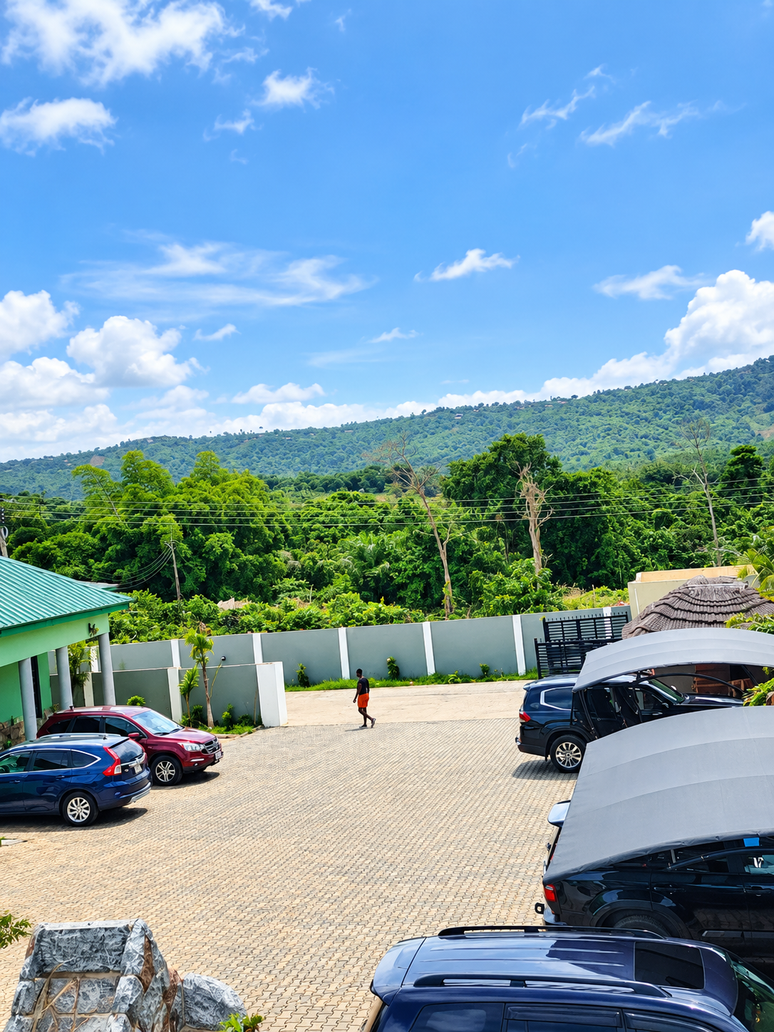 Hotel parking area with green hillside views