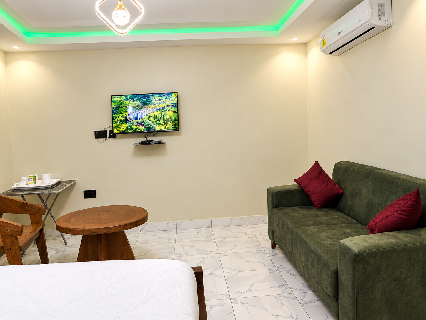Guest room with a bed, green sofa, television and air conditioning