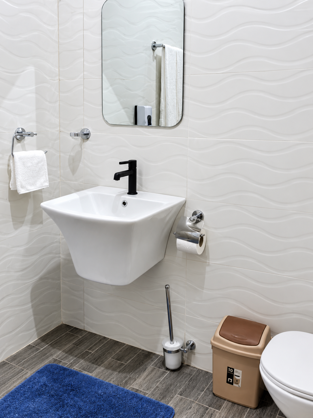Modern bathroom washbasin with black tap, mirror and textured white wall tiles