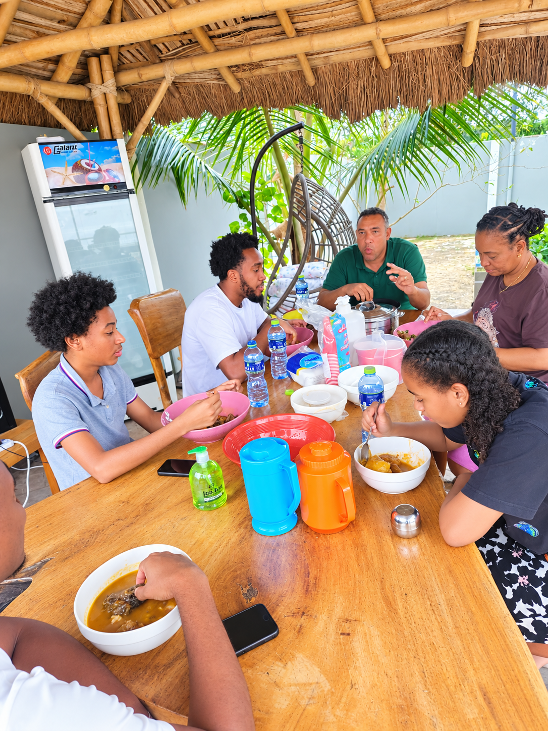 Family sharing a meal under a thatched gazebo