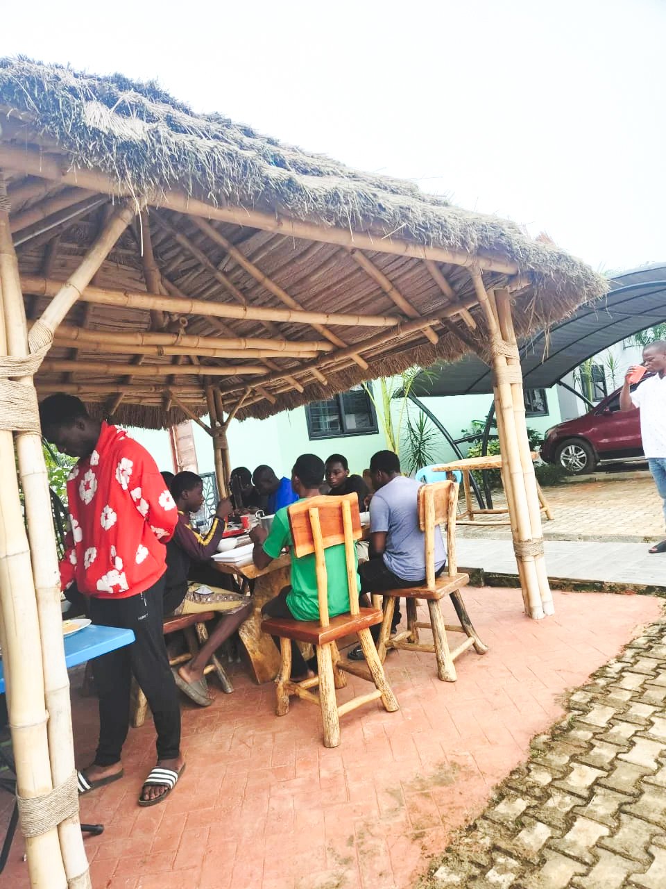 Guests gathered around a table beneath a traditional thatched-roof pavilion